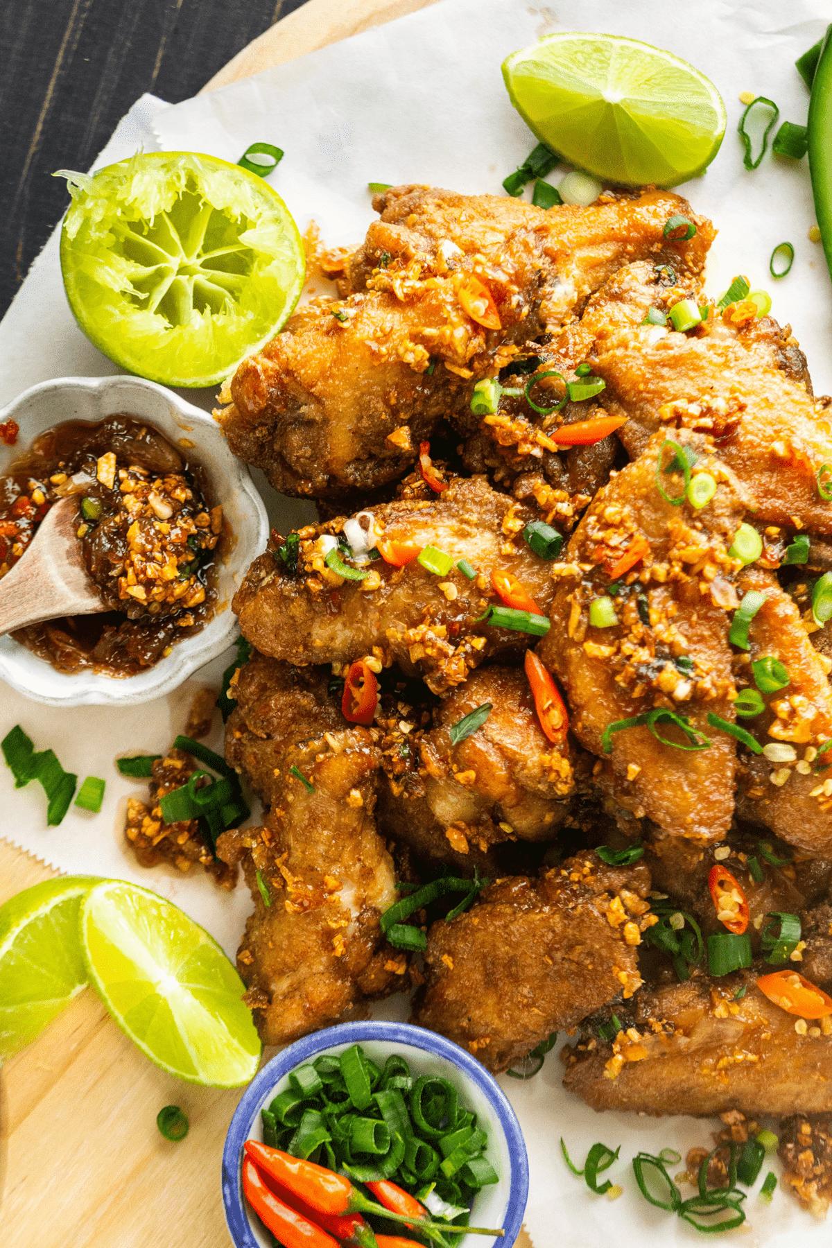 Fish Sauce Chicken Wings on a board with a dish of sauce next to it and some lime.