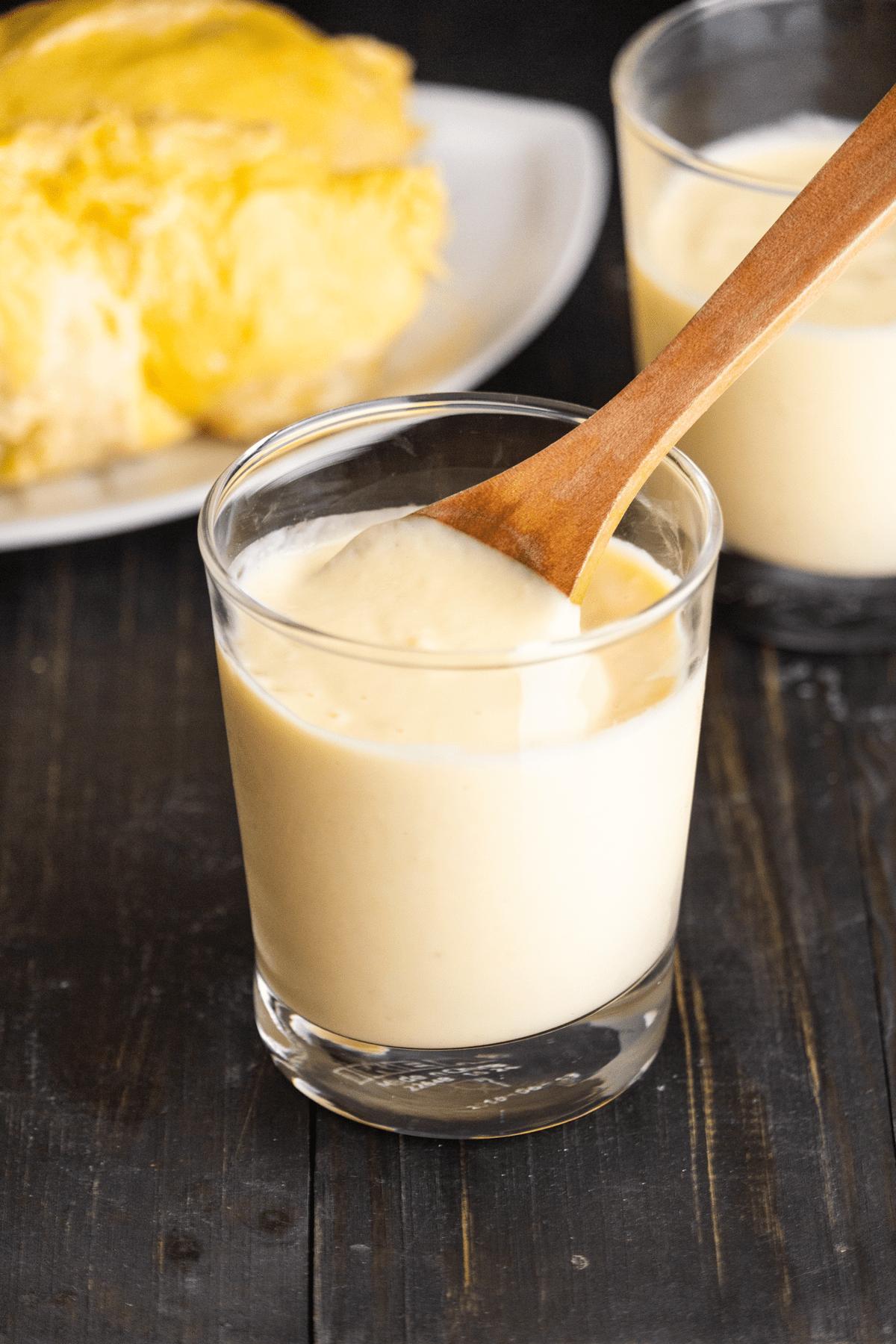 Sinh Tố Sầu Riêng in a glass cup with a spoon in it.